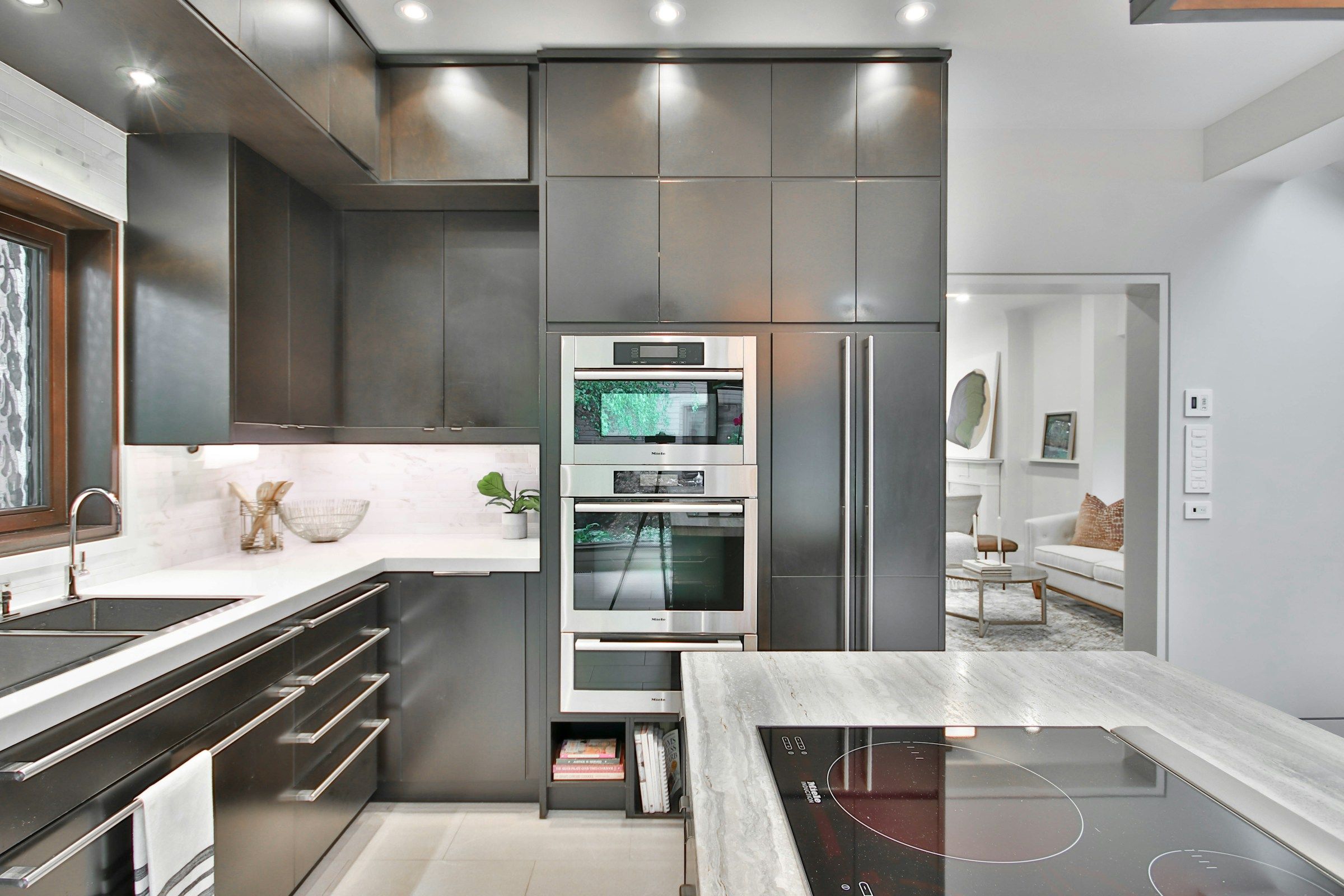 A modern kitchen with marble counters, lit for a listing shoot